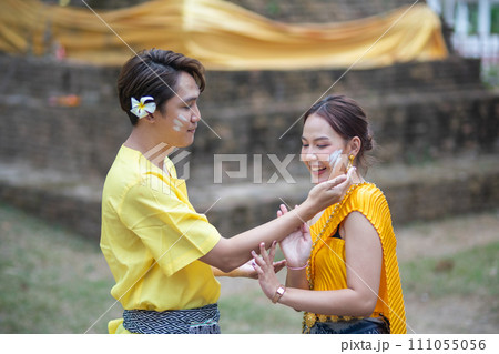 A beautiful Young Thai couple wearing Thai costumes playing in the water during Songkran in the temple A beautiful Young Thai couple wearing Thai costumes playing in the water during Songkran in the temple 111055056