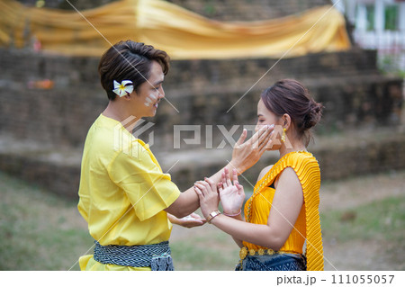 A beautiful Young Thai couple wearing Thai costumes playing in the water during Songkran in the temple A beautiful Young Thai couple wearing Thai costumes playing in the water during Songkran in the temple 111055057