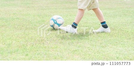 公園の芝生でサッカーをする子どもの足元（サッカーボール・ドリブル） 111057773
