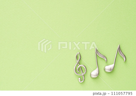 音楽イメージ　黄緑色の紙に置かれたト音記号と8分音符のオブジェ 111057795