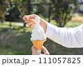 手に持ったソフトクリームをスプーンですくう 111057825