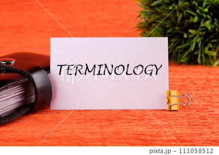 TERMINOLOGY text written on a white card near the business card holder in black on an orange background 111058512
