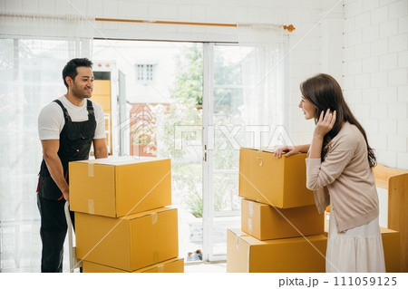 Professional movers aid couple indoors unloading boxes from truck into the home. Service guarantees customer satisfaction during relocation. Teamwork and efficient assistance portrayed. Moving day Professional movers aid couple indoors unloading boxes from truck into the home. Service guarantees customer satisfaction during relocation. Teamwork and efficient assistance portrayed. Moving day 111059125