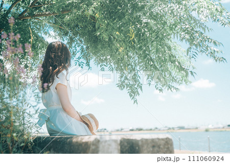 夏に木陰で休む白いワンピースの女性 111060924
