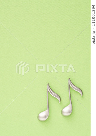 音楽イメージ　黄緑色の紙に置かれた8分音符のオブジェ 111061294