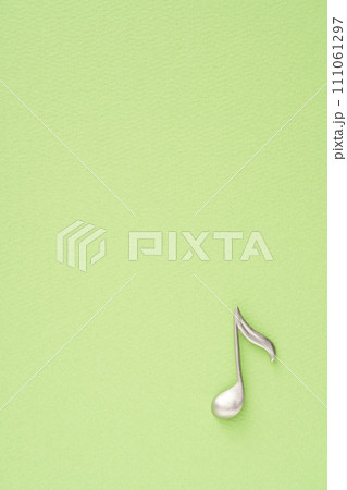 音楽イメージ　黄緑色の紙に置かれた8分音符のオブジェ 111061297