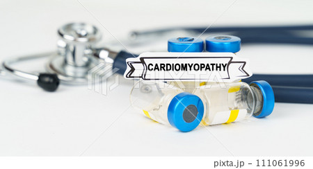 On the table there is a stethoscope, injections and a sign with the inscription - cardiomyopathy On the table there is a stethoscope, injections and a sign with the inscription - cardiomyopathy 111061996
