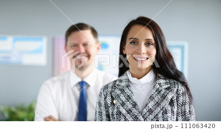 Smiling employees man and woman stand in office Smiling employees man and woman stand in office 111063420