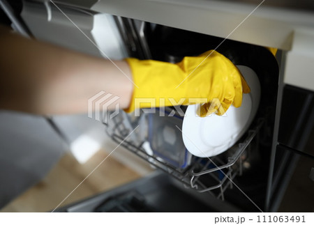 Hands in gloves put plate to dishes in dishwasher 111063491