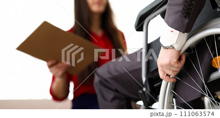 Man in suit on wheelchair communicates with woman Man in suit on wheelchair communicates with woman 111063574