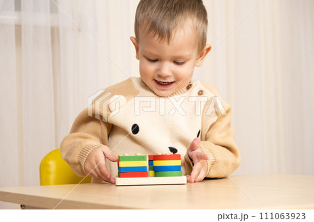 Little boy playing with wooden multicolored Montessori toys. Little boy playing with wooden multicolored Montessori toys. 111063923