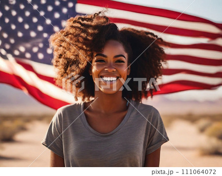 Portrait of a happy beautiful black girl with curly hair against the background of the USA flag in the desert 111064072