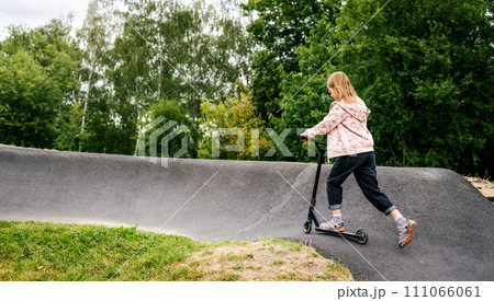 Preteen girl riding scooter on ramp in the park. Cute child with eco vehicle outdoors 111066061