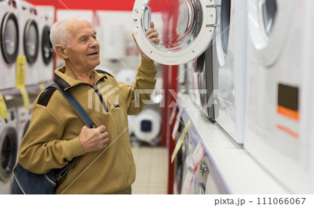 Elderly man choosing washing machine in showroom of electrical appliance store Elderly man choosing washing machine in showroom of electrical appliance store 111066067