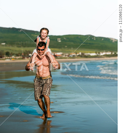Father holding daughter at shoulders at sea coast and running. Family dad and pretty smiling child kid at beach at summer Father holding daughter at shoulders at sea coast and running. Family dad and pretty smiling child kid at beach at summer 111066110