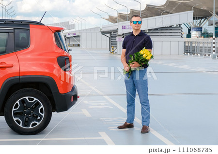 Man with a bouquet of flowers in the airport parking lot. Man with a bouquet of flowers in the airport parking lot. 111068785