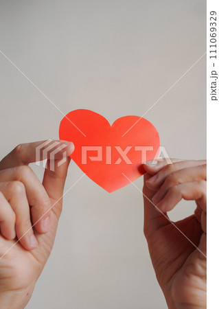 women's hands holding red heart shaped postcard, surprise gift for Valentine's day. 111069329
