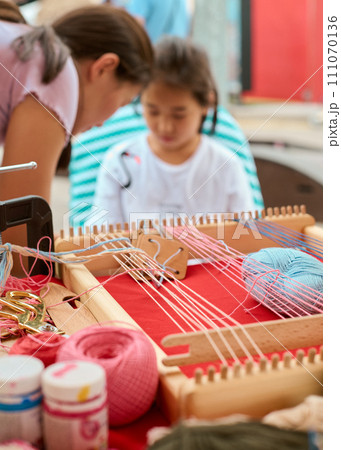Weaving loom, threads, carpet creating. Making colored tapestry, close up Weaving loom, threads, carpet creating. Making colored tapestry, close up 111070136