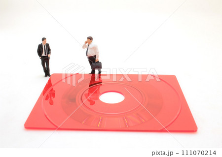 Business figurine standing on a compact disk 111070214