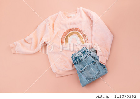 Children's pink sweater and blue jeans on a pink background 111070362