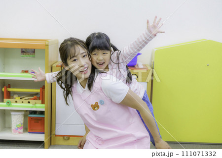 保育園で保母さんの背中に乗ってはしゃぐ女の子 撮影協力:有明教育芸術短期大学 保育園で保母さんの背中に乗ってはしゃぐ女の子 撮影協力:有明教育芸術短期大学 111071332