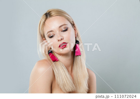 Attractive fashion model woman with blonde hair wears big pink color earrings. Fashionable lady  111072024