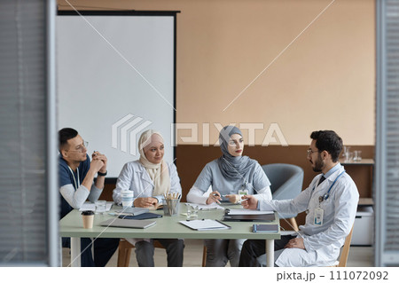 Medium full shot of Muslim medical interns listening to experienced male supervisors instructions during meeting in clinic office Medium full shot of Muslim medical interns listening to experienced male supervisors instructions during meeting in clinic office 111072092