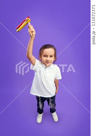 Top view photo of little boy, Jewish kid looking at camera and shows grogger to camera against purple background. Celebration Purim. Top view photo of little boy, Jewish kid looking at camera and shows grogger to camera against purple background. Celebration Purim. 111072371