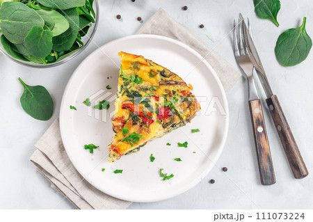 Piece of egg frittata with spinach, roasted peppers, mushrooms, cheese, horizontal, top view 111073224