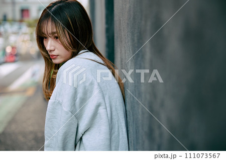 壁に寄りかかる若い女性 111073567