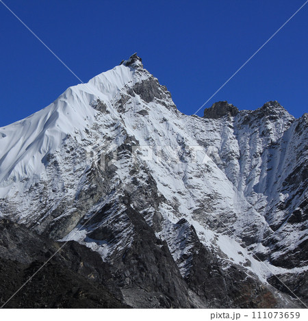 Blue sky over a snow covered peak seen from Gorakshep, Nepal. 111073659