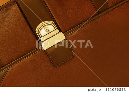 Briefcase from genuine leather close-up, texture. Detail of leather briefcase, metal clasp, background 111076838