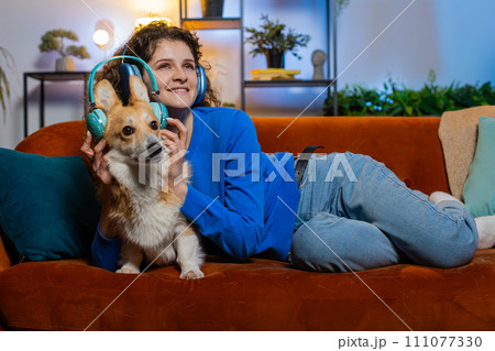 Joyful relaxed woman listening to smartphone music through wireless headphones lying on sofa dancing Joyful relaxed woman listening to smartphone music through wireless headphones lying on sofa dancing 111077330