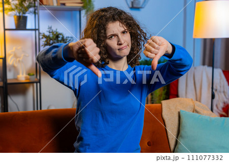 Displeased upset young woman showing thumbs down dislike gesture expressing discontent disapproval 111077332