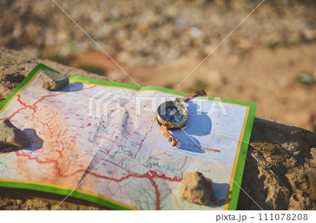 Close-up of an old compass and geographic map on a rock. Trip. Tourism 111078208
