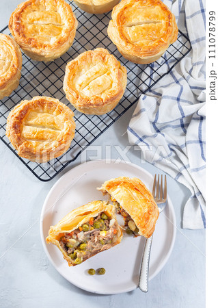 Sliced beef pot pie on plate and pies on cooling rack, vertical, top view Sliced beef pot pie on plate and pies on cooling rack, vertical, top view 111078799