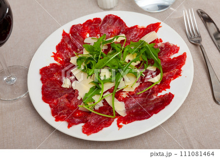 Carpaccio with cheese and arugula served on plate 111081464