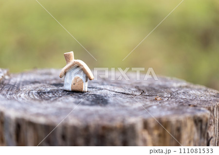 丸太の切株の上に置いてある素焼き陶器のかわいい素朴な煙突のついた小さなおうち 111081533