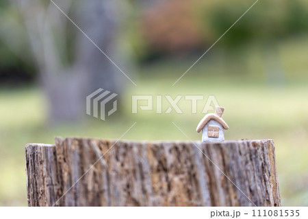 丸太の切株の上に置いてある素焼き陶器のかわいい素朴な煙突のついた小さなおうち 111081535