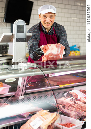Butcher demonstrating slice of fresh raw veal sirloin 111081566