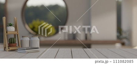 A space on a wooden plank table in a modern, minimalist living room with a round window. 111082085