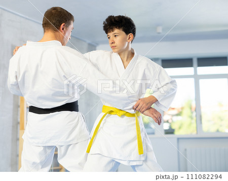 Teenage boy applying judo techniques on middle-aged trainer during sports classes Teenage boy applying judo techniques on middle-aged trainer during sports classes 111082294