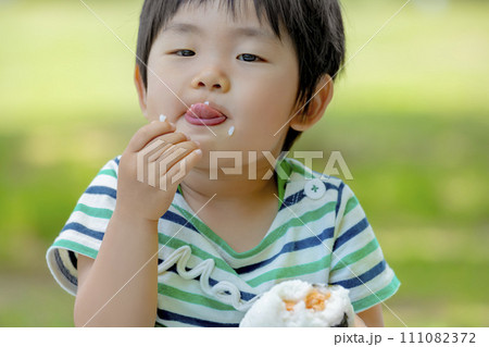 公園でおにぎりを食べる男の子 111082372