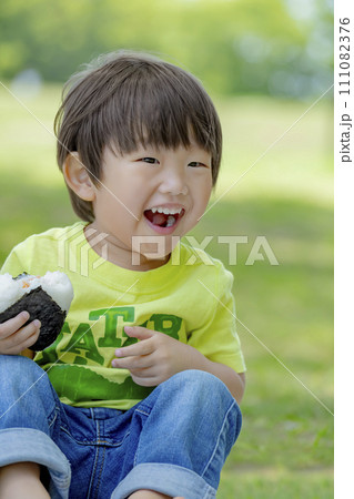 公園でおにぎりを食べる男の子 111082376