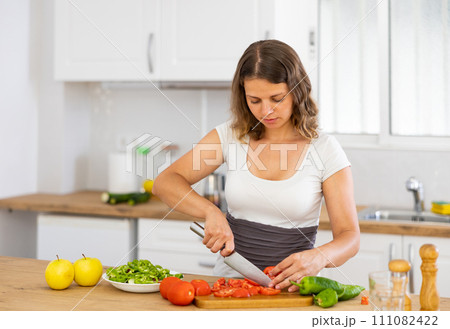 Portrait of woman cutting vegetable on kitchen 111082422