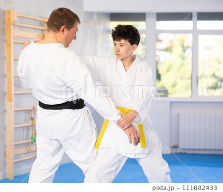Coach teaches judo techniques to teenager during individual training Coach teaches judo techniques to teenager during individual training 111082433