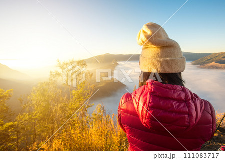Back view of Asian women standing on the hill and looking to the beautiful sunrise and sea of fog over Bromo Tengger Semeru National Park in East Java, Indonesia. Back view of Asian women standing on the hill and looking to the beautiful sunrise and sea of fog over Bromo Tengger Semeru National Park in East Java, Indonesia. 111083717