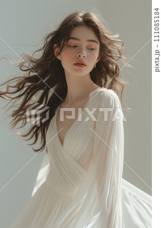 A woman elegantly adorned in a flowing white long dress 111085184