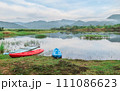 Landscape  boat on the lake reflects a blue sky. The cloudy sky is reflected in the mirror like smooth lake surface. 111086623