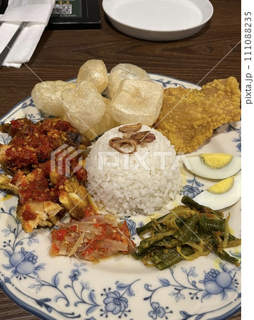 Indonesian food with rice and some of meat, chicken and vegetables in a plate 111088235